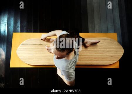 Junger Mann, der Yoga auf einem Yoga-Brett praktiziert. Stockfoto