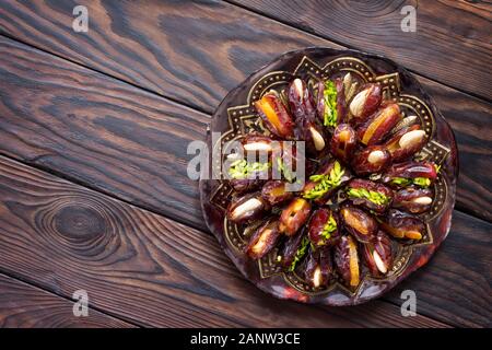 Getrocknete Datteln gefüllt mit kandierten Früchten und Nüssen auf einem rustikalen Holztisch. Ansicht von oben flach Hintergrund mit kopieren. Stockfoto
