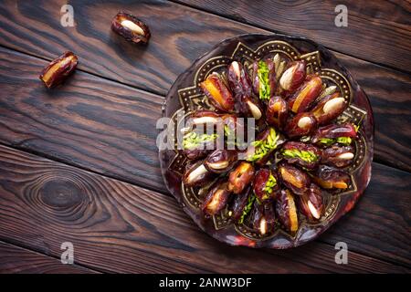 Getrocknete Datteln gefüllt mit kandierten Früchten und Nüssen auf einem rustikalen Holztisch. Ansicht von oben flach Hintergrund mit kopieren. Stockfoto