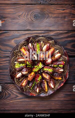 Getrocknete Datteln gefüllt mit kandierten Früchten und Nüssen auf einem rustikalen Holztisch. Ansicht von oben flach Hintergrund mit kopieren. Stockfoto