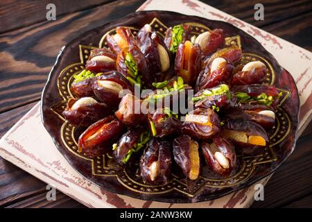 Getrocknete Datteln gefüllt mit kandierten Früchten und Nüssen auf einem rustikalen Holztisch. Stockfoto