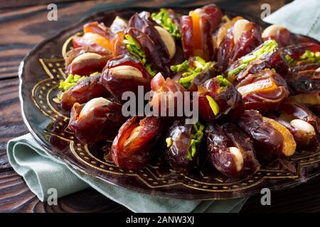 Getrocknete Datteln gefüllt mit kandierten Früchten und Nüssen auf einem rustikalen Holztisch. Stockfoto