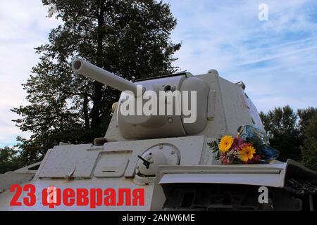 23. Februar Grußkarte. Militärische Tank, Blume auf natürliche Hintergrund. Gerne Verteidiger des Vaterlandes Tag in Russischer Sprache. Stockfoto