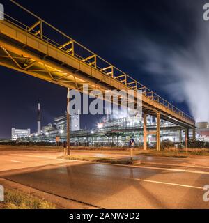Nachtaufnahme mit beleuchteten petrochemische Produktionsanlage und Pipeline Überführung, Antwerpen, Belgien. Stockfoto