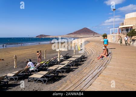 EL Medano, Spanien - 7. JULI 2019: Menschen zu Fuß auf Promenade und Surfen, Kiten und Windsurfen in Granadilla de Abona Gemeinde Stockfoto