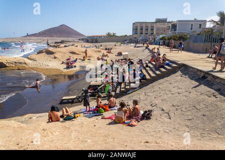 EL Medano, Spanien - 7. JULI 2019: Menschen zu Fuß auf Promenade und Surfen, Kiten und Windsurfen in Granadilla de Abona Gemeinde Stockfoto