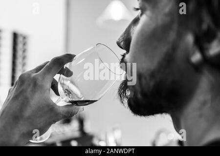 Mann Gesicht Seite selektiven Fokus Nahaufnahme, wie er trinkt ein Glas roten Wein, Alkohol Gefahr Konzept in Schwarz und Weiß Stockfoto