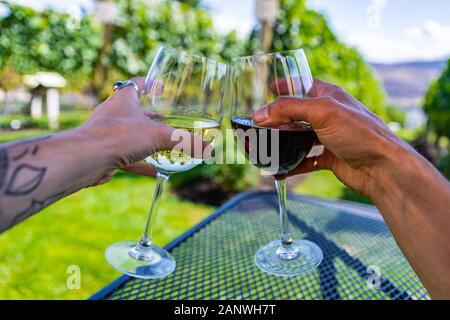 Mann und Frau Hände jubelnd Weingläser, da sie gegen die schöne Landschaft von Weingut Weinberge sitzend, glückliches Paar auf Wein Verkostung outdoor Reise Stockfoto