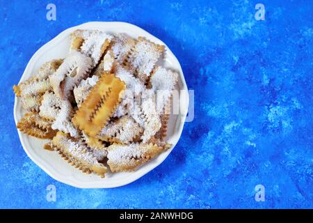 Blick von oben auf die hausgemachten traditionellen Karneval Süßwaren: chiacchiere auf blauem Hintergrund. Kopieren Sie Platz. Stockfoto