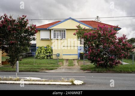 Hohes wetterfestes Vorstadthaus nach dem Krieg, darunter eine geschlossene Garage, in der Vorstadt von Brisbane und in Cannon Hill, mit städtischer Topografie Stockfoto