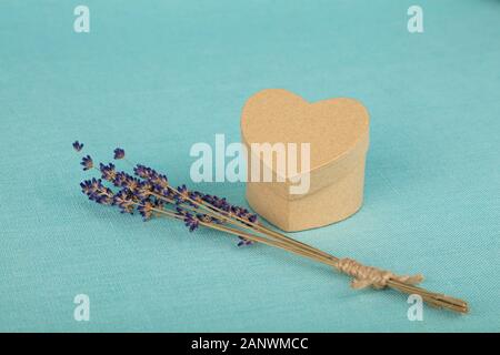 Close up Bukett von getrockneten Lavendelblüten und kleinen herzförmigen Geschenkbox auf Blau Tischdecke, hohe Betrachtungswinkel Stockfoto