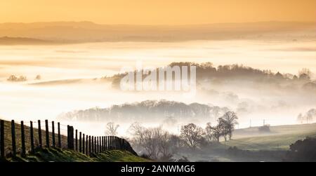 Ethereal Blick vom Gipfel des untergehenden Sonne im nebligen Tal in Dorset, Großbritannien Stockfoto