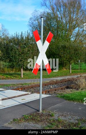 Unbeaufsichtigte Bahnübergang mit St. Andrew's Cross im Sonnenlicht mit blauer Himmel Stockfoto