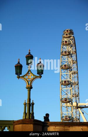 Man Walking Vergangenheit verzierten Straßenlaterne auf die Westminster Bridge und London Eye/Millennium Wheel in London, England Stockfoto