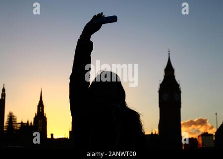 Silhouette von Mädchen unter selfie mit Big Ben im Hintergrund bei Sonnenuntergang, South Bank, London, England. Fokus auf Mädchen. Stockfoto