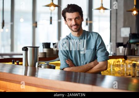 Berufliche Tätigkeit. Barkeeper stehen an der Theke an verschränkten Armen lächelt Fröhlich Stockfoto