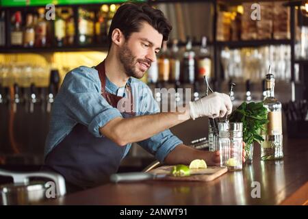 Trinken Vorbereitung. Barkeeper stehen an der Theke Mischen von Zutaten in Glas konzentriert Stockfoto