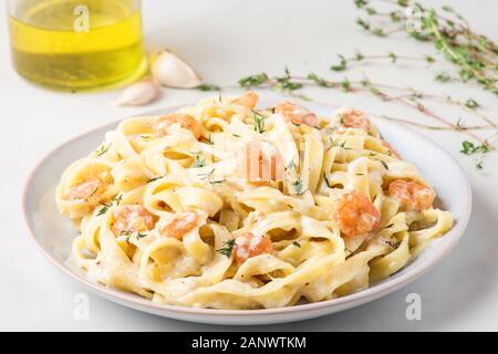 Nudeln Bandnudeln mit Krabben oder Garnelen in Rahmsauce und Thymian in eine Platte auf weißer Tisch. Italienische Küche. Nach oben Schließen Stockfoto