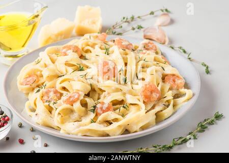 Italienische Pasta Fettuccine oder Tagliatelle in eine cremige Soße mit Garnelen in eine Platte auf weißem Marmor tisch. Nach oben Schließen Stockfoto
