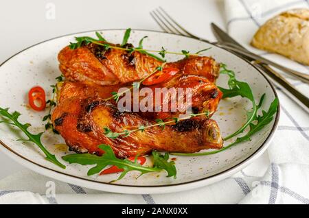 Gebraten würzige Hähnchenkeulen oder Drumsticks auf einem weißen Teller. Köstliche Mittag- oder Abendessen. Stockfoto