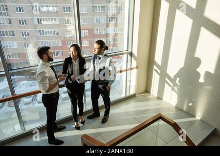Gruppe von drei jungen, zeitgenössischen Analysten in formale diskutieren online Daten Stockfoto