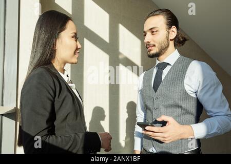 Zwei junge interkulturelle Kollegen in formale Diskussion Arbeitspunkte Stockfoto