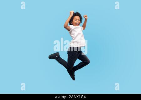 Volle Länge, lebhafte energischer kleiner Junge in T-Shirt und Jeans springen in die Luft schreien mit Glück, Kind, Fliegen, Gefühl verrückt inspiriert und Ove Stockfoto