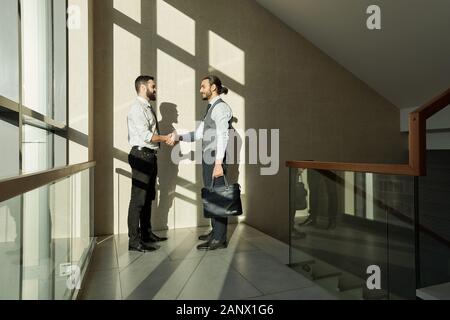 Zwei junge elegante Business Partner handshaking nach Unterzeichnung eines neuen Vertrags Stockfoto