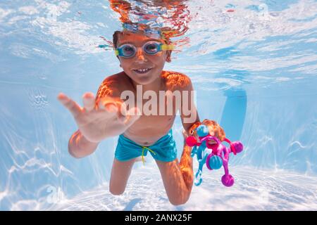 Kleines Kind Schwimmen unter Wasser sammeln Spielzeug in den Pool tragen Googles macht Spaß schwimmen Übung