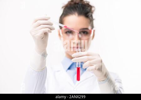 Die Hände des Arztes fallen rote Flüssigkeit Substanz in Kolben mit neuer Impfstoff Stockfoto