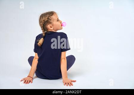 Mädchen bläst eine Blase von Kaugummi auf weißem Hintergrund Stockfoto