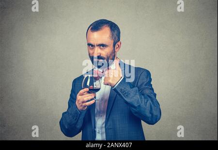 Es ist ein guter Wein. Happy Elegant mann Winzer halten ein Glas Rotwein mit Daumen hoch, wie Geste mit der Hand. Gemischte Rasse bearded Modell isoliert Stockfoto