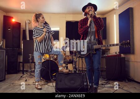 In voller Länge Porträt der zeitgenössischen Musik Band genießen Singen mit schönen Frau und bärtige Gitarristen im Vordergrund, Kopie Raum Stockfoto