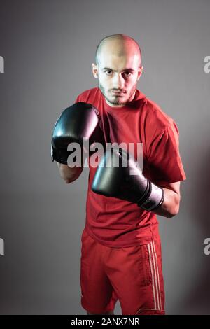 Boxer bereitet sich auf Kampf steht in schwarzen Handschuhen Blick nach vorne Zu roten Shorts rotes T-Shirt Stockfoto