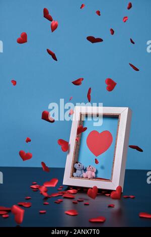 Herzen fallen und schwebenden aller in einem Bild in Bezug über den Tag des Valentine, ein Bilderrahmen mit Herz, ein paar kleine Teddybären. Stockfoto