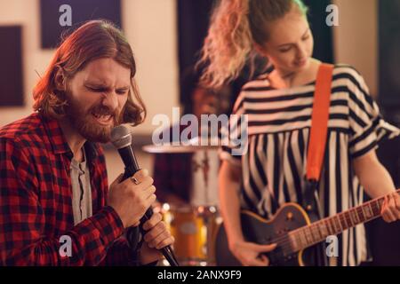 Portrait von bärtigen Mann singen Wild auf das Mikrofon während der Probe oder ein Konzert mit Musik Band im Studio, Kopie Raum Stockfoto