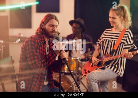 Portrait von bärtigen Mann singen auf das Mikrofon während der Probe oder ein Konzert mit Musik Band im Studio, Kopie Raum Stockfoto