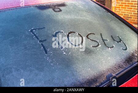 UK Wetter: das Wort "Frosty" auf einem vereisten Windschutzscheibe von einem roten Auto auf einem kalten, frostigen Morgen im Winter, Surrey, South East England geschrieben, Großbritannien Stockfoto