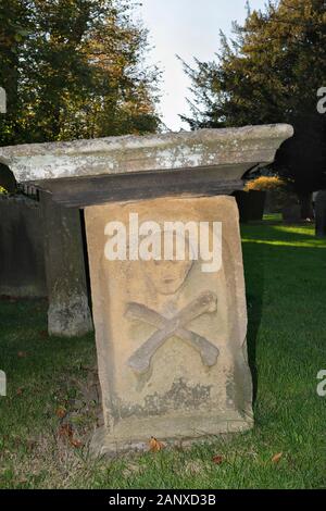 Schädel und Kreuzknochen am Ende des Grabes 7 in Eyam Village Churchyard, Derbyshire, England, Großbritannien, 17. Jahrhundert, Grad II. Gelistet Stockfoto