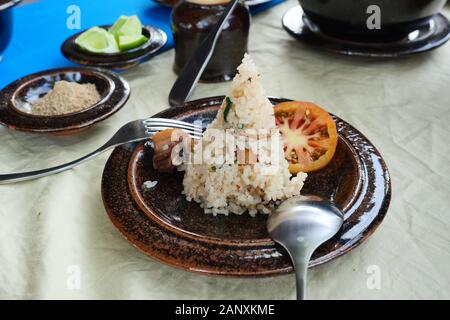Zongzi oder traditionelles Chinesisch klebrigen Reis Knödel mit in Scheiben geschnittenen Tomaten mit Löffel und Gabel auf braun Teller, chinesisches Essen mit Platte von Pfeffer und Kalk Stockfoto