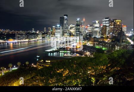 Weiter Blick auf das Stadtbild des CBD in Sydney bei Nacht mit leichten wegen vom Fährverkehr im Circular Quay Stockfoto