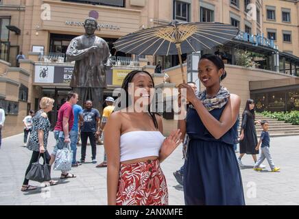 Johannesburg, Südafrika. 19 Jan, 2020. Die Einheimischen, die eine traditionelle chinesische Öl- papier Regenschirm posieren für Fotos während der Feierlichkeiten für das bevorstehende chinesische Mondjahr in Johannesburg, Südafrika, Jan. 19, 2020. Hunderte von chinesischen und Südafrikaner aller Altersgruppen aus verschiedenen Hintergründen zusammen bei Nelson Mandela Square in Johannesburg am Sonntag chinesische Mondjahr zu feiern. Eine Anzahl der ausübenden Künstler sowohl in China und Südafrika die Teilnehmer mit Musik und Tanz unterhalten. Credit: Chen Cheng/Xinhua/Alamy leben Nachrichten Stockfoto