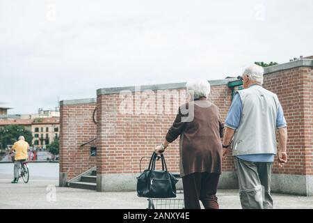 Ein älteres Paar oder Senioren spazieren oder wandern entlang der Fußgängerzone. Stockfoto