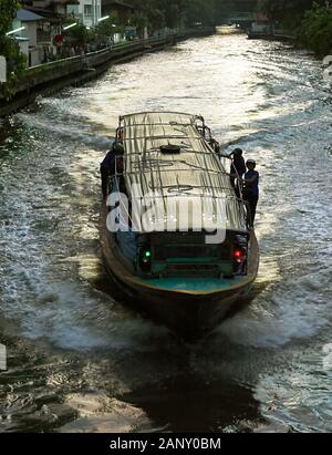 Bangkok, Thailand: idyllische Aussicht auf den Sonnenuntergang junger Menschen auf ein Boot, das mit hoher Geschwindigkeit auf einer khlong Wasserstraße hängend, Wellen Stockfoto