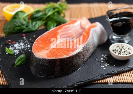 Ungekochter Lachs Steak und Gewürzen bereit für das Kochen auf schwarzem Schiefer. Gesund, reich an Omega 3 gesunde Fettsäuren Fisch und Meeresfrüchte Stockfoto