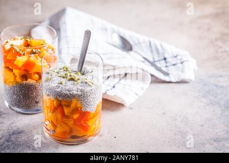 Chia Pudding mit Dattel und Kürbiskerne in Gläser, grauen Hintergrund. Gesunde vegane Ernährung Konzept. Stockfoto