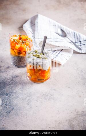 Chia Pudding mit Dattel und Kürbiskerne in Gläser, grauen Hintergrund. Gesunde vegane Ernährung Konzept. Stockfoto