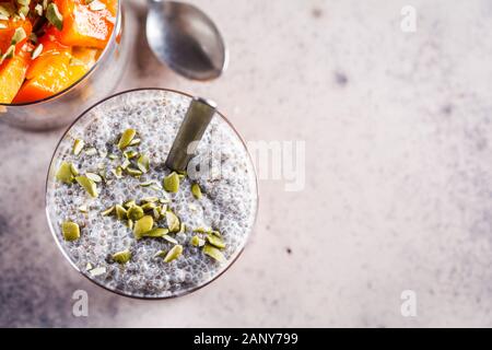 Chia Pudding mit Dattel und Kürbiskerne in Gläser, grauen Hintergrund. Gesunde vegane Ernährung Konzept. Stockfoto