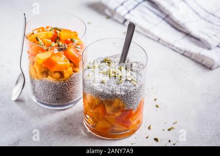 Chia Pudding mit Dattel und Kürbiskerne in Gläser, grauen Hintergrund. Gesunde vegane Ernährung Konzept. Stockfoto