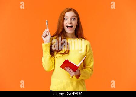 Inspiriert und verträumt, smart rothaarige Studentin erhielt hervorragende Idee für Ihr Buch, Schreiben im Notebook Pläne und To-do-Liste, die Pen in Eureka Stockfoto